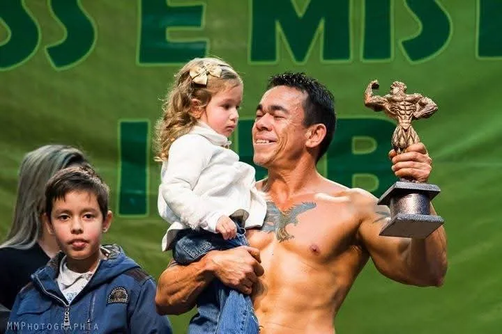 Huck Pereira no pódio segurando o troféu e a filha no colo